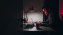 An email marketer working late, a coiled string of festive bulbs beside the keyboard